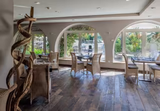 Salle de restaurant aux fenêtres en arcades, ouvertes sur le jardin