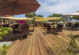 Terrasse en bois du bar, avec tables, parasols et bougainvilliers