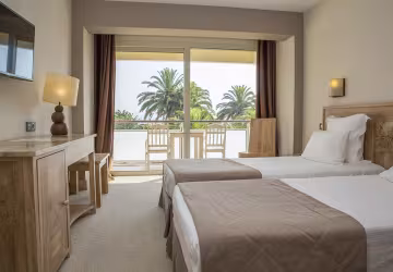 Chambre à deux lits avec balcon donnant sur les palmiers