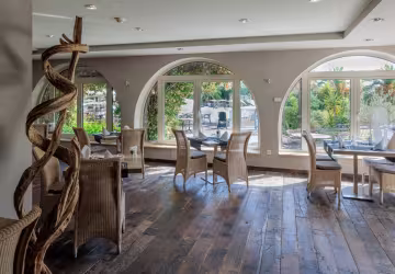 Salle de restaurant aux fenêtres en arcades, ouvertes sur le jardin