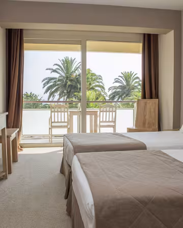Chambre à deux lits avec balcon donnant sur les palmiers