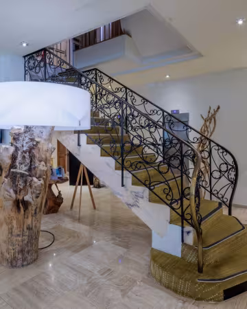 Hall de l'hôtel, avec son escalier en fer forgé et sa lampe en bois flotté