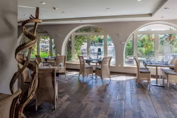 Salle de restaurant aux fenêtres en arcades, ouvertes sur le jardin
