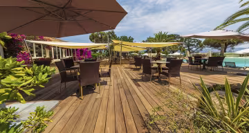 Terrasse en bois du bar, avec tables, parasols et bougainvilliers