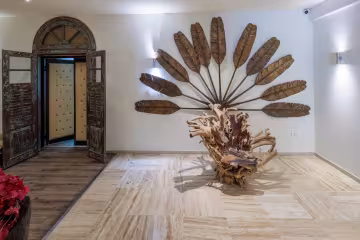 Hall de l'hôtel avec une sculpture en bois flotté et un décor de feuilles de palmier